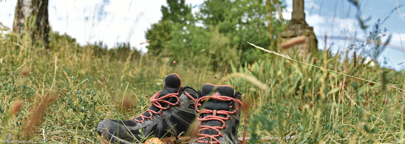 Pilgerschuhe und -stab am Kreuzweg